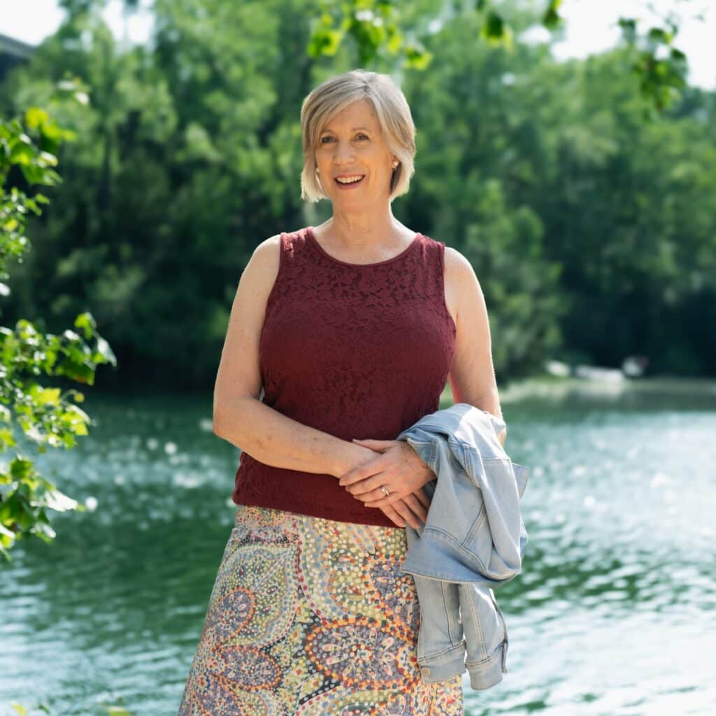 Amy Armstrong standing in front of a lake with trees in the background